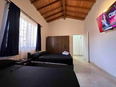 a room with two beds and a television in it at Casa Tradicional Remodelada en Envigado con Patio in Envigado