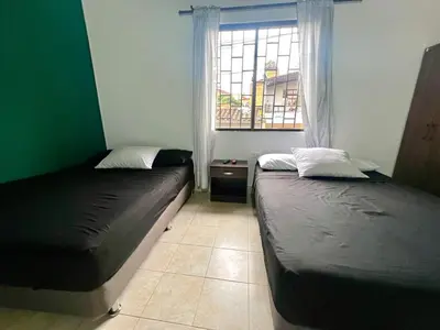 two beds in a room with a window at Casa Tradicional Remodelada en Envigado con Patio in Envigado