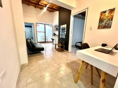 a room with a desk and a living room at Casa Tradicional Remodelada en Envigado con Patio in Envigado