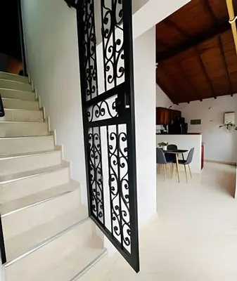 a black iron door with a staircase in a house at Duplex con terraza en el corazón de Envigado 300mb in Envigado