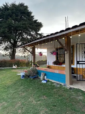 a house with a porch with a tree in the background at Santaelena Cielo · Retiro natural cerca al Parque Arví Wi-Fi Starlink in Medellín