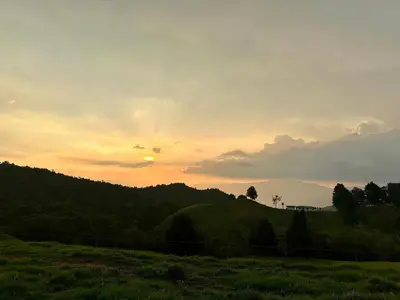 a sunset over a grassy field with the sun in the sky at Santaelena Cielo · Retiro natural cerca al Parque Arví Wi-Fi Starlink in Medellín