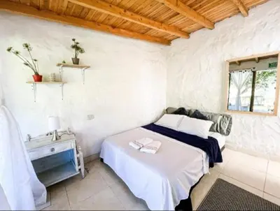 a white bedroom with a bed and a window at Los Lagos de Jasú in San Vicente