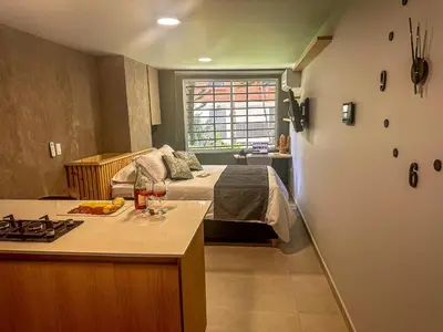 a bedroom with a bed and a kitchen with a counter at Edificio Atalanta en el corazón de Medellín in Medellín