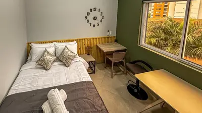 a bedroom with a bed and a desk and a window at Edificio Atalanta en el corazón de Medellín in Medellín