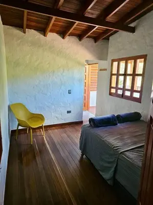 a bedroom with a bed and a yellow chair at Tranquilidad y Naturaleza Cabaña Concepción in Concepción