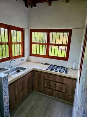 a kitchen with a sink and a stove and windows at Tranquilidad y Naturaleza Cabaña Concepción in Concepción