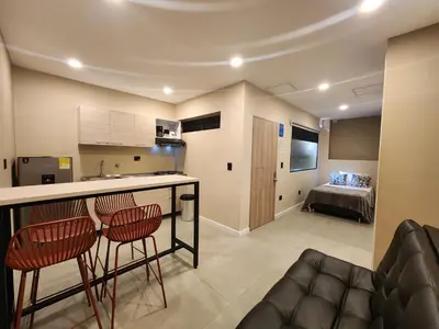 a kitchen and living room with a bar and chairs at Loft 10, Comodo Aparta estudio 201 in Medellín