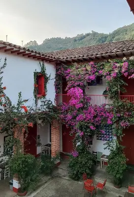 a building with flowers on the side of it at La Oculta Hostal in Jericó