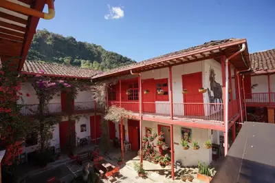 an apartment building with red doors and balconies at La Oculta Hostal in Jericó