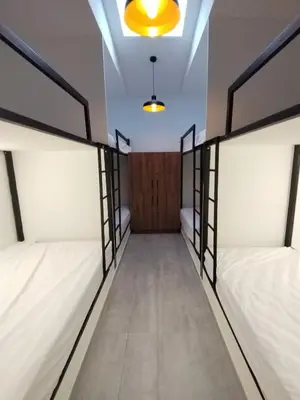 a row of beds in a room with a door at Hostal The Nest By Ulivin in Manizales