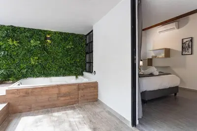 a bathroom with a tub with a green wall at ENCANTO - Provenza Private Villa with Heated Pool & Hot Tub Encanto NOWA in Medellín