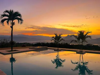 a pool with a palm tree and a sunset at Fina Estampa Country Hotel - Mayores de 10 años in Támesis