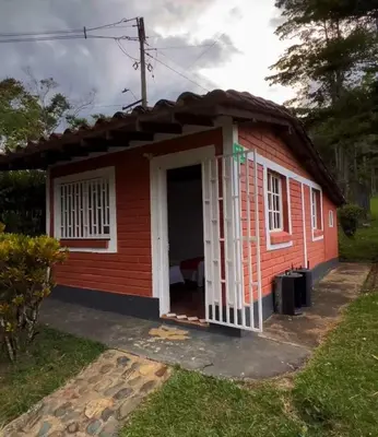 a small red house with a white door at Yarumito Finca Hotel l Cabaña Pensamiento in Barbosa