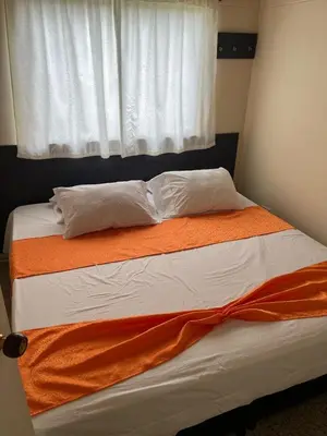 a bed with an orange blanket and a window at Yarumito Finca Hotel l Cabaña Pensamiento in Barbosa