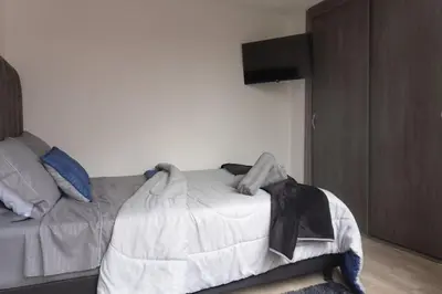 a bedroom with a bed and a tv on a wall at Apartamento en el Cable mejor zona en Manizales in Manizales