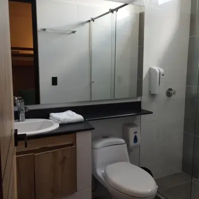 a bathroom with a toilet and a sink and a mirror at Hotel Luna Verde in Doradal