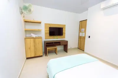 a bedroom with a bed and a desk with a television at Hotel Luna Verde in Doradal