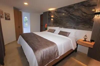 a bedroom with a large bed with a stone wall at Hotel y Termales Castillo Del Lago Guatape in Horizonte