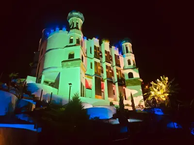 a large building with lights on it at night at Hotel y Termales Castillo Del Lago Guatape in Horizonte