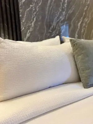 a bed with white sheets and a pillow on it at Hotel y Termales Castillo Del Lago Guatape in Horizonte