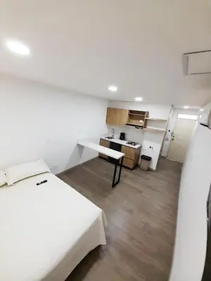 a room with two beds and a desk in it at Medellin cómodo apartaestudio 503 in Medellín