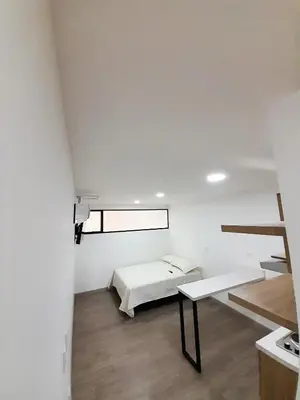 a white room with a bed and a table at Medellin cómodo apartaestudio 503 in Medellín