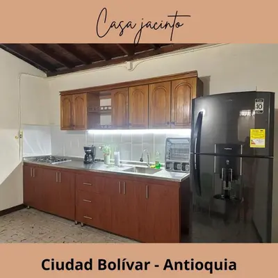 a kitchen with wooden cabinets and a black refrigerator at Casa Jacinto in Ciudad Bolívar