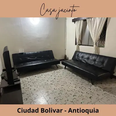 a living room with a black leather couch and a tv at Casa Jacinto in Ciudad Bolívar
