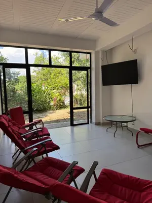 a living room with red chairs and a flat screen tv at Acogedora cabaña en la Pintada in La Pintada