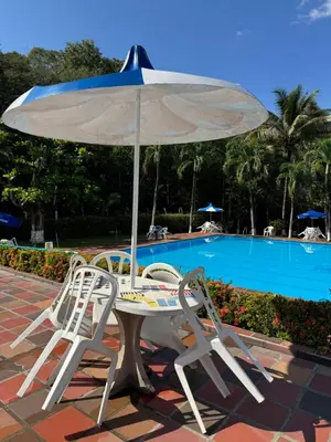 a table and two chairs under an umbrella next to a pool at Acogedora cabaña en la Pintada in La Pintada
