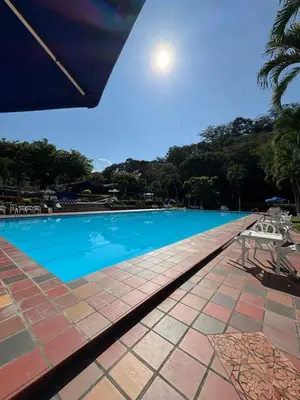 a large blue swimming pool with a table and chairs at Acogedora cabaña en la Pintada in La Pintada