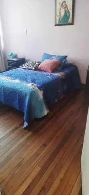 a bed with a blue comforter on a wooden floor at Casa para ferias manizales in Manizales