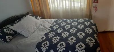 a bed with a blue and white blanket and pillows at Casa para ferias manizales in Manizales