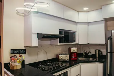 a kitchen with white cabinets and a black counter top at Paco House in Jardin