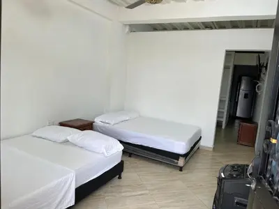 two beds in a room with a room with a suitcase at Apartamento Napoles in Doradal