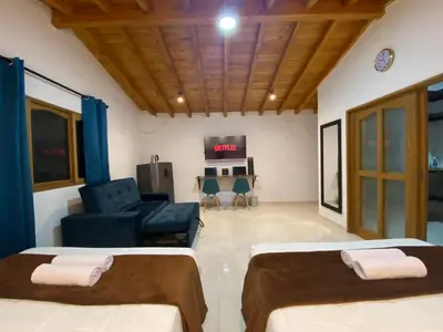 a room with two beds and a couch and a tv at Fraternity Room, Habitación Deluxe - solo a una cuadra del parque in Carmen de Viboral