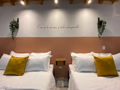 two beds in a room with a sign on the wall at Fraternity Room, Habitación Deluxe - solo a una cuadra del parque in Carmen de Viboral