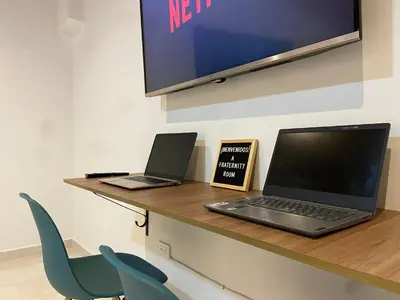 two laptops sitting on a desk with a tv at Fraternity Room, Habitación Deluxe - solo a una cuadra del parque in Carmen de Viboral