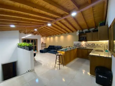 a large kitchen with wooden ceilings and a living room at Casa Dorada - Confort a solo una cuadra del Parque in Carmen de Viboral