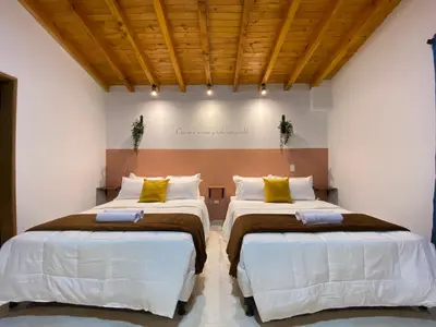 two beds in a room with white walls and wooden ceilings at Casa Dorada - Confort a solo una cuadra del Parque in Carmen de Viboral