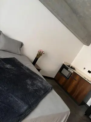 a bedroom with a bed and a vase of flowers at Encantador Loft urbano en el corazón de Medellín in Medellín