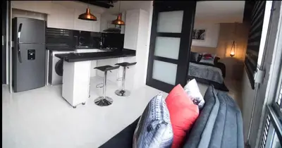 a living room with a couch and a kitchen at EXCLUSIVO APARTAMENTO para disfrutar Medellin in Medellín