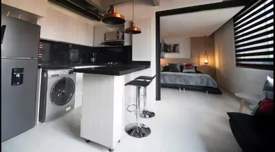 a kitchen with a washing machine and a bed in a room at EXCLUSIVO APARTAMENTO para disfrutar Medellin in Medellín