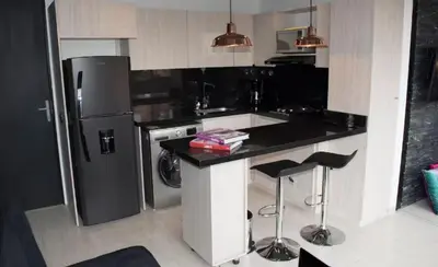 a kitchen with a refrigerator and a counter with stools at EXCLUSIVO APARTAMENTO para disfrutar Medellin in Medellín