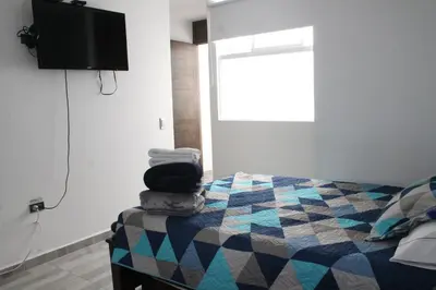 a bedroom with a bed and a tv on the wall at Apartahotel Avverato in Guatapé