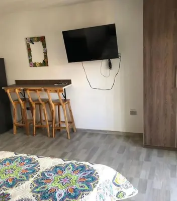 a room with a table and a television on a wall at Apartahotel Avverato in Guatapé