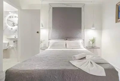 a white bedroom with a bed with a towel on it at El Poblado 4 Bedroom 3 Bathroom private Terrace in Medellín
