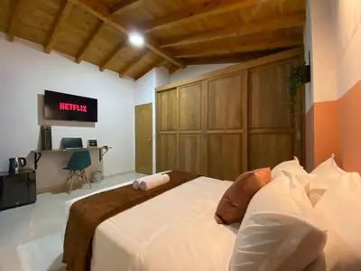 a bedroom with a bed and a tv on the wall at Prosperity Room, Habitación doble - solo a una cuadra del parque in Carmen de Viboral