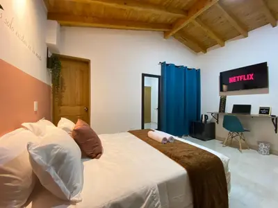 a bedroom with a large bed and a television at Prosperity Room, Habitación doble - solo a una cuadra del parque in Carmen de Viboral